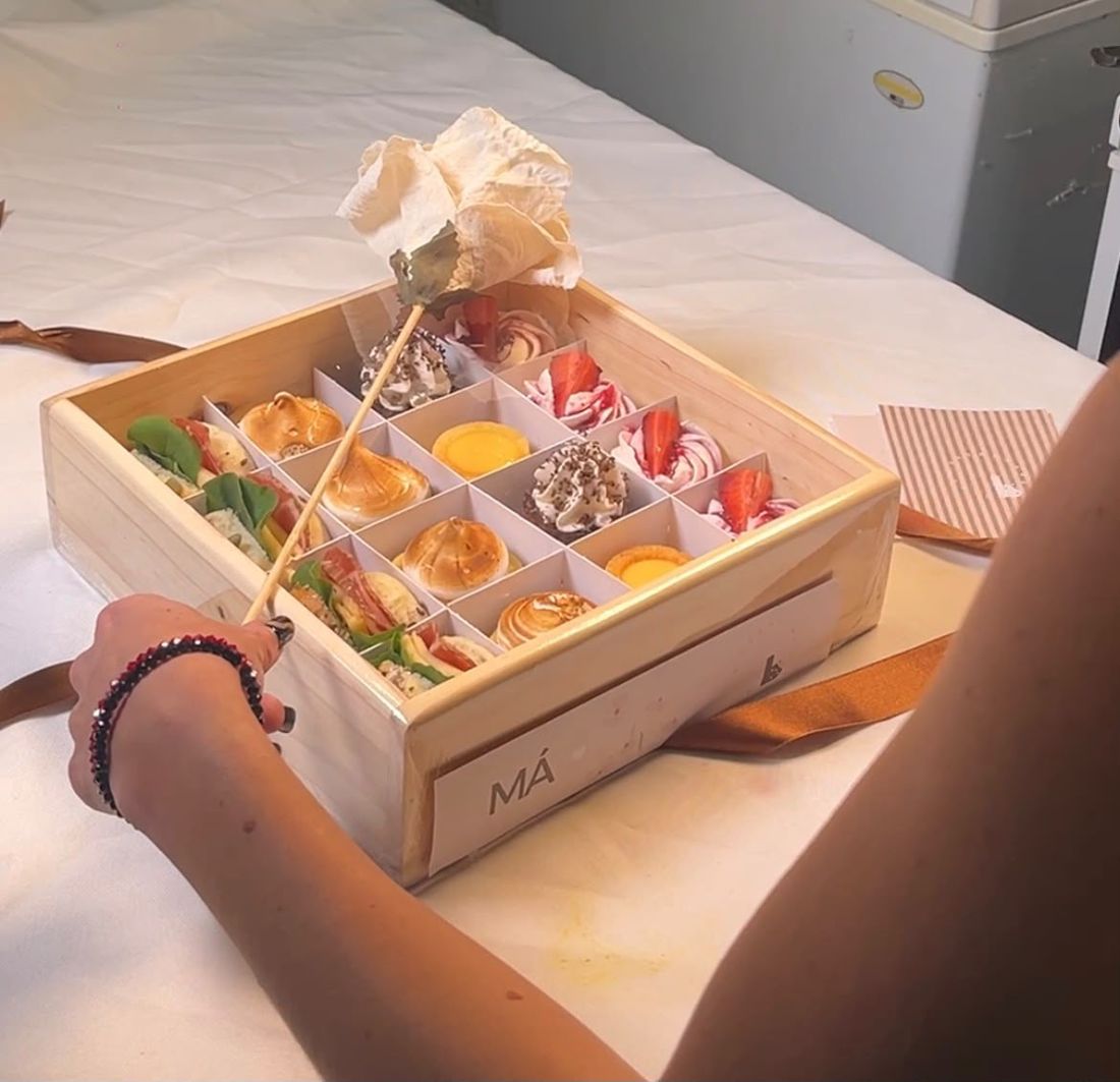 Caja de madera abierta con merengues, tartas de limón y sándwiches